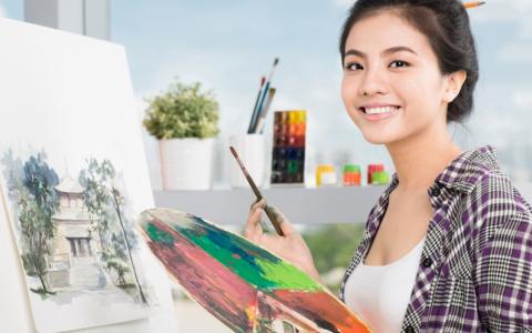 Student artist smiling with paint brush and paint palette
